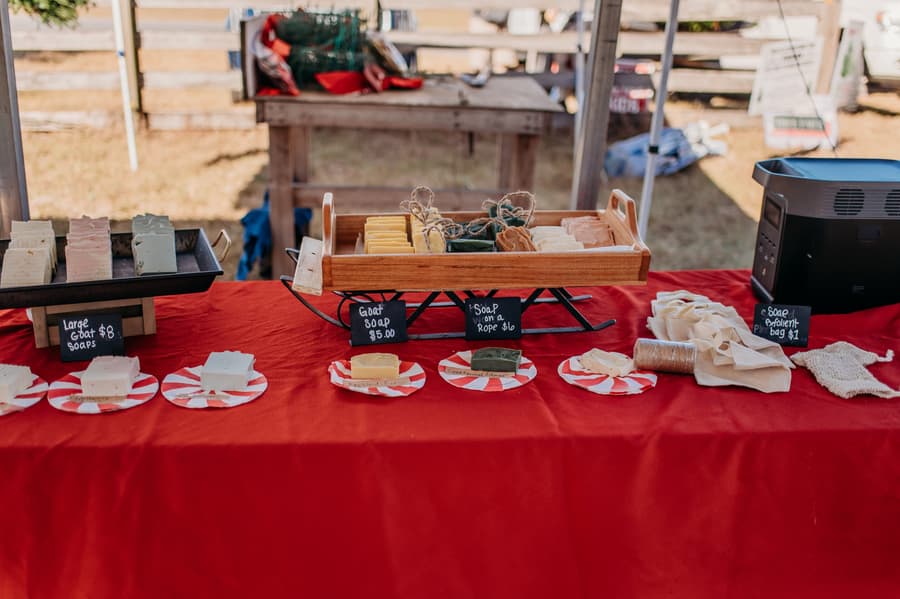 Handmade goat milk soaps on a red table at a vendor booth
